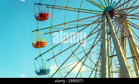Riesenrad mit bunten Kabinen auf dem blauen Himmel Hintergrund. Detail des farbigen Riesenrads gegen Wolken. Konzept von Urlaub und Kinder`s amu Stockfoto